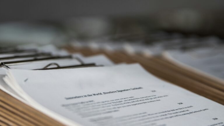 Close-up of an open menu page with a signature cocktail description, part of a row of clipboard-bound menus lined up on a table, shot at a shallow depth of field
