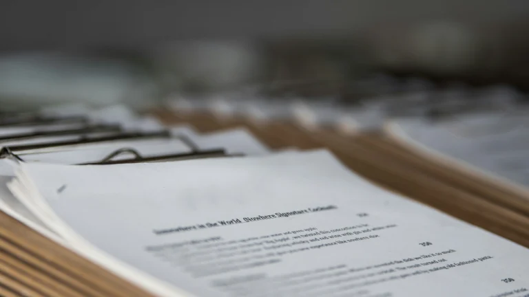 Close-up of an open menu page with a signature cocktail description, part of a row of clipboard-bound menus lined up on a table, shot at a shallow depth of field